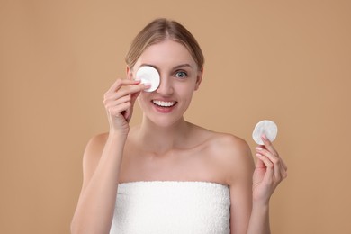 Photo of Young woman with cotton pad on beige background