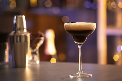 Photo of Glass of Espresso Martini on counter in bar, space for text. Alcohol cocktail