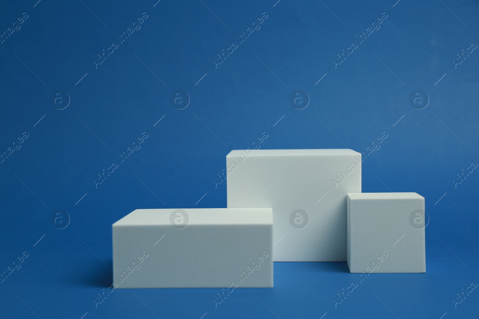 Photo of Product photography props. Podiums of different geometric shapes on blue background