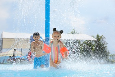 Photo of Cute little children having fun in swimming pool at water park