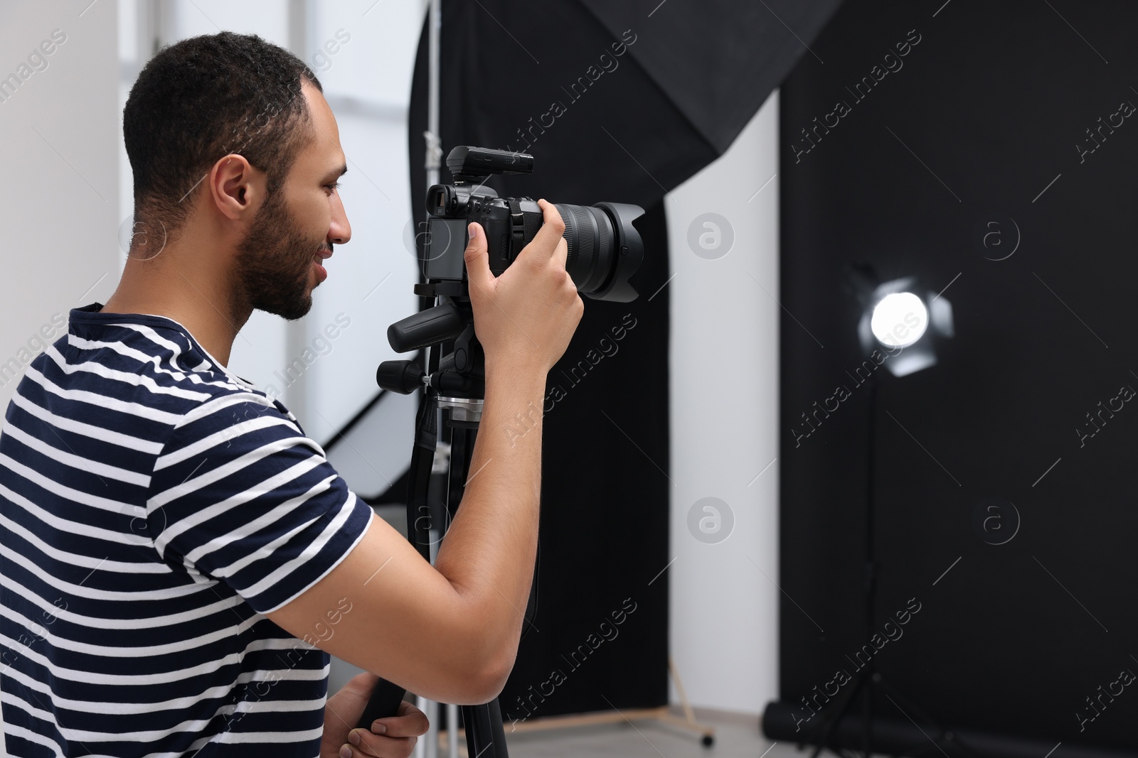 Photo of Young professional photographer with camera in modern photo studio, space for text