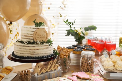 Photo of Baby shower party. Different delicious treats on wooden table and decor indoors