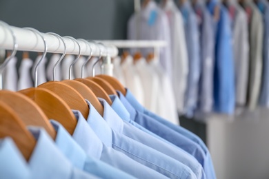 Photo of Rack with clean clothes on hangers after dry-cleaning indoors