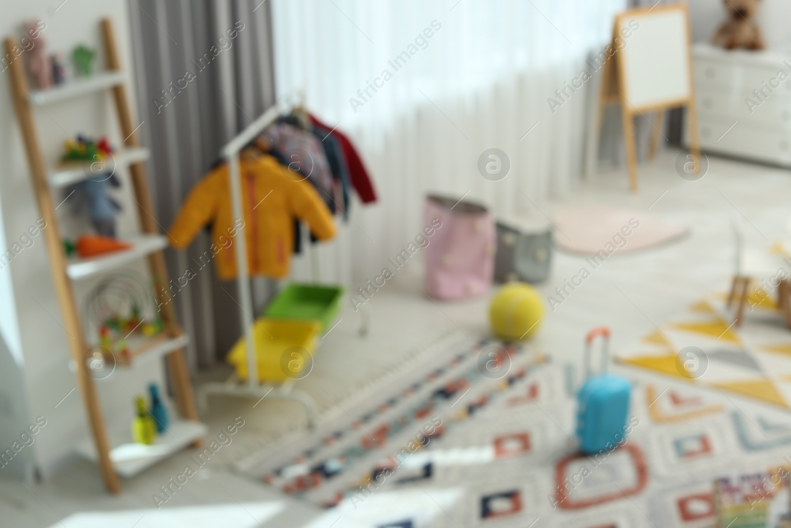 Photo of Blurred view of child`s playroom with different toys and furniture. Stylish kindergarten interior