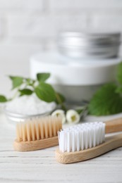 Toothbrush, dental products and herbs on white wooden table, closeup