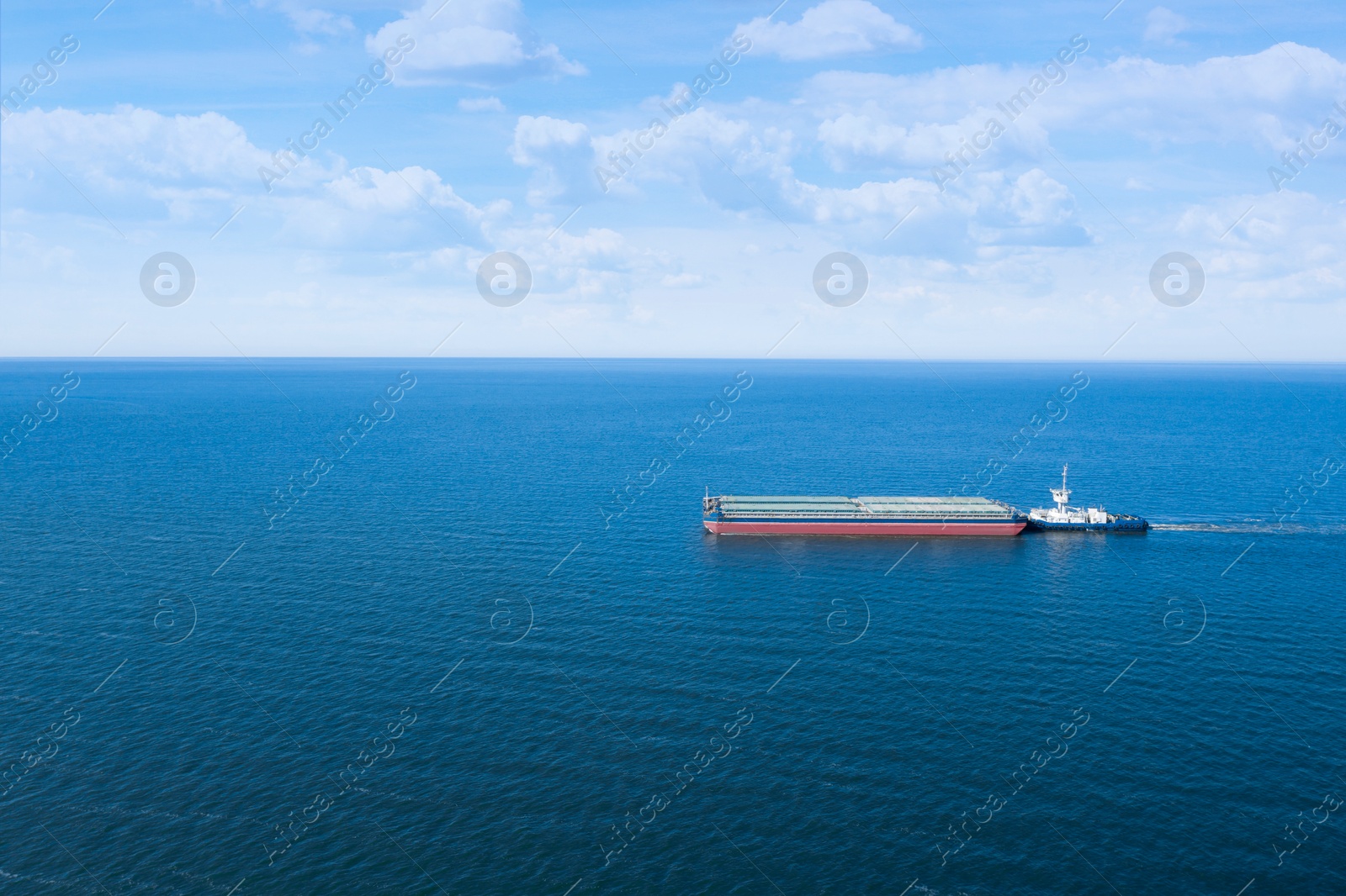Image of Tugboat pulling barge with cargo by water, aerial view