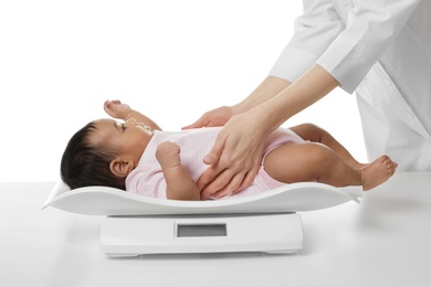 Doctor weighting African-American baby on scales against white background