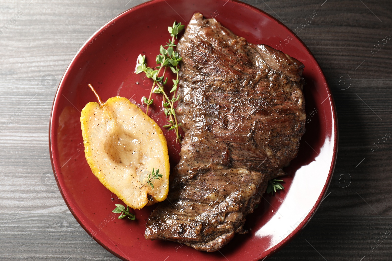 Photo of Delicious roasted beef meat, caramelized pear and thyme on grey wooden table, top view