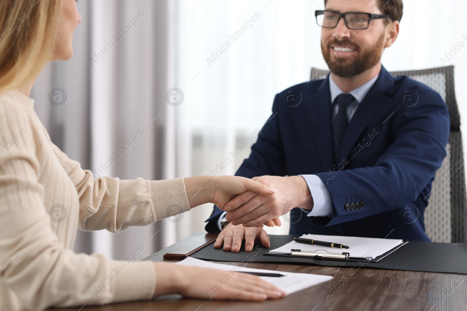 Photo of Lawyer shaking hands with client in office, selective focus