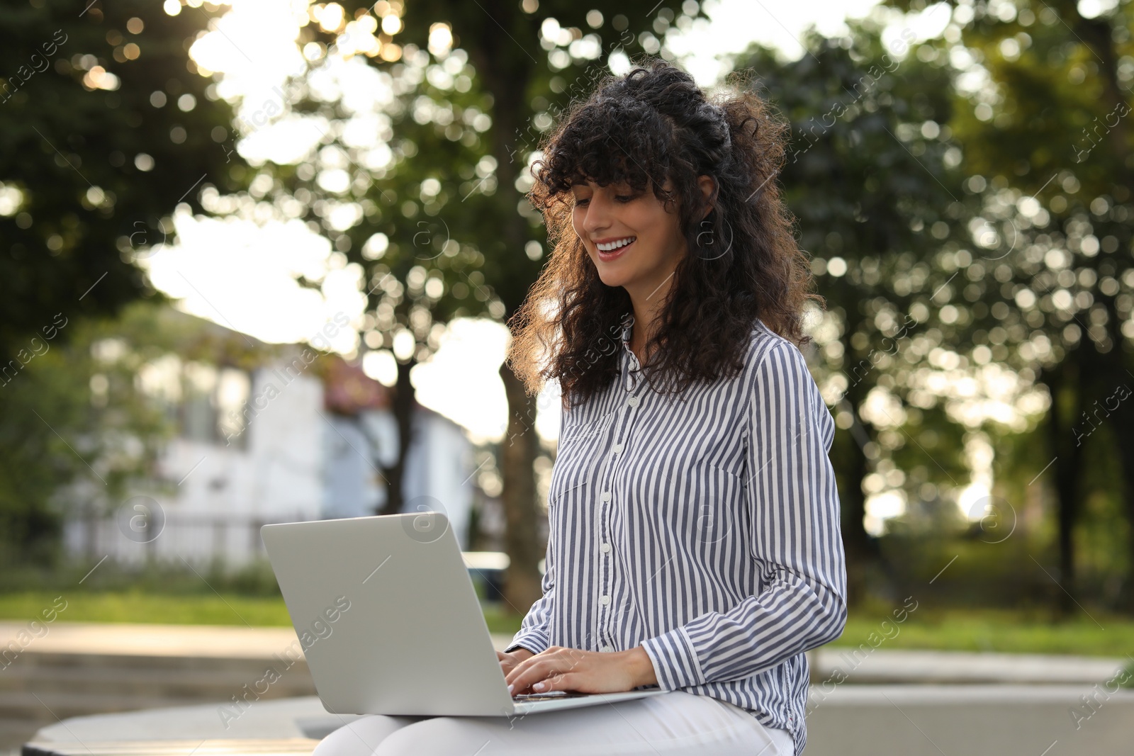 Photo of Happy young woman using modern laptop outdoors