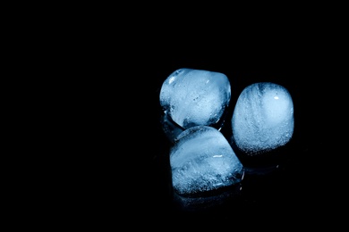 Photo of Melting ice cubes on black background. Space for text