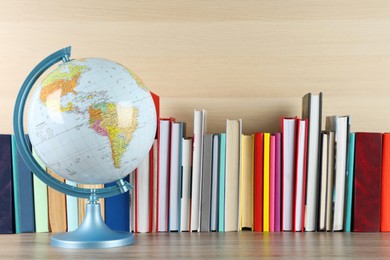 Photo of Globe and many books on wooden table. Geography lesson