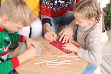 Cute children with their parents making beautiful Christmas greeting cards at home