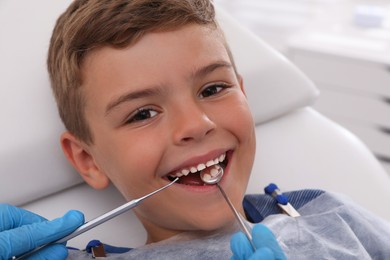 Dentist examining little boy's teeth in modern clinic, closeup