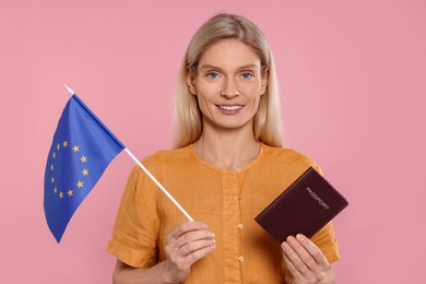 Immigration. Happy woman with passport and flag of European Union on pink background