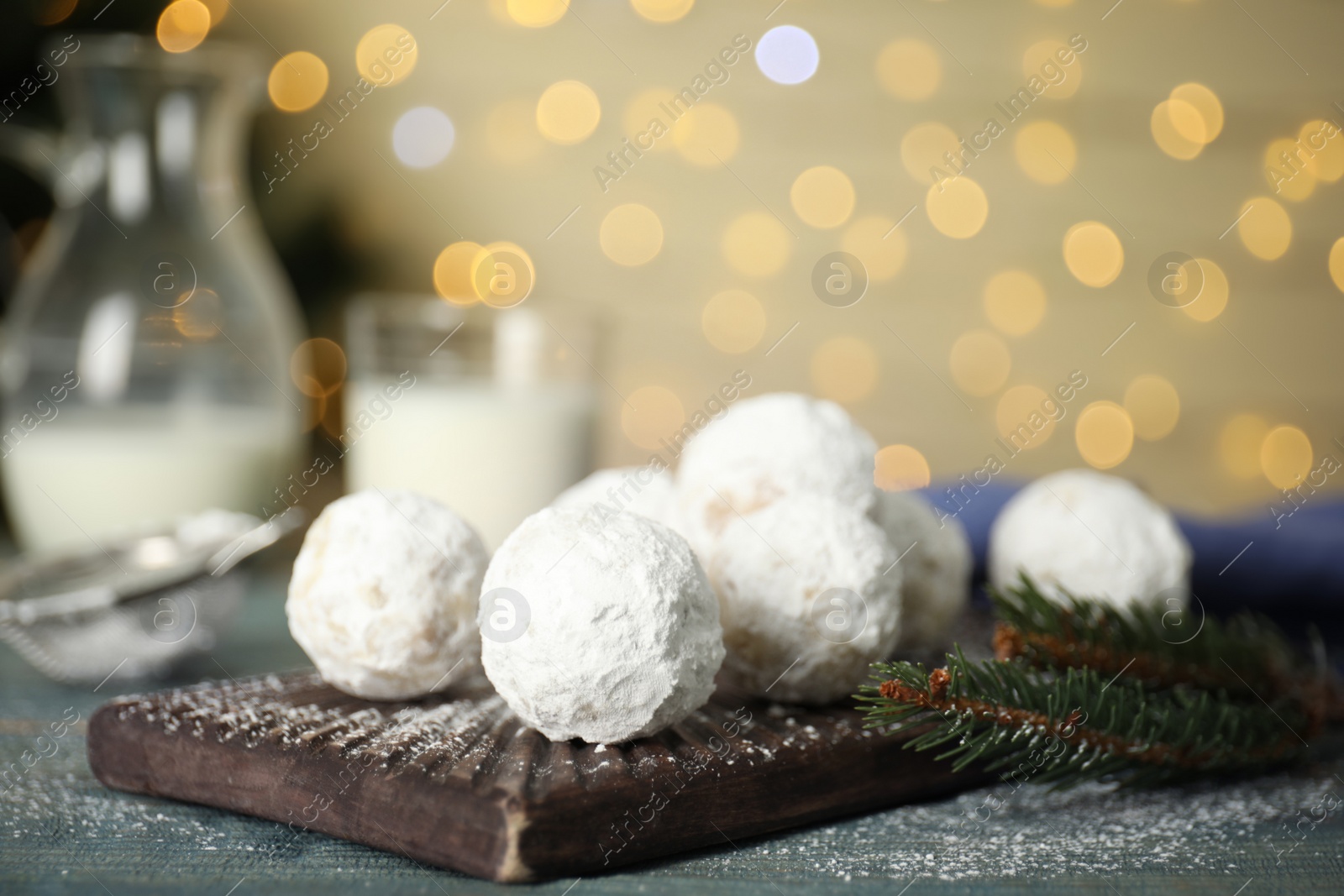 Photo of Christmas snowball cookies and fir tree branch on table, closeup. Space for text