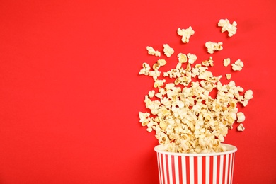 Paper cup with tasty fresh popcorn on color background, top view