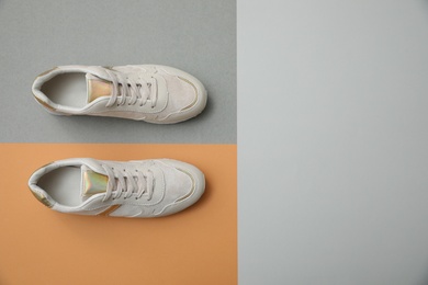 Stylish white shoes on color background, top view
