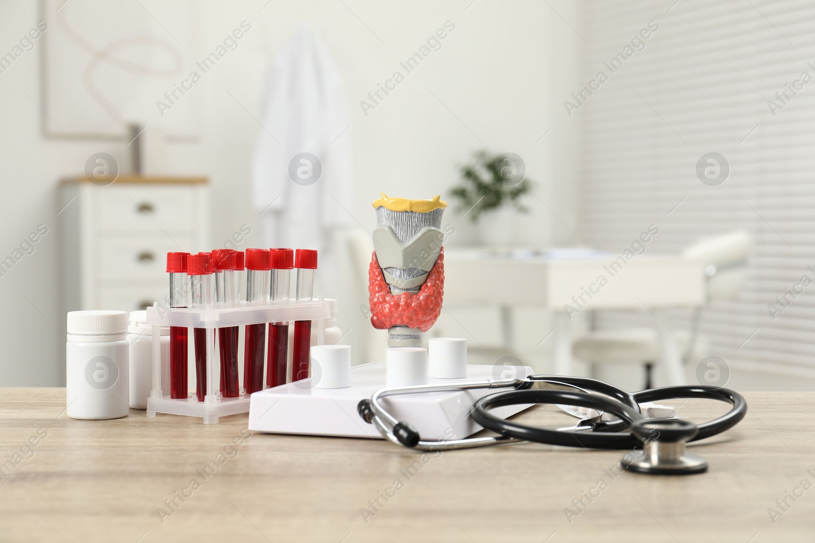 Photo of Endocrinology. Stethoscope, model of thyroid gland and blood samples in test tubes on table indoors