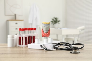 Photo of Endocrinology. Stethoscope, model of thyroid gland and blood samples in test tubes on table indoors