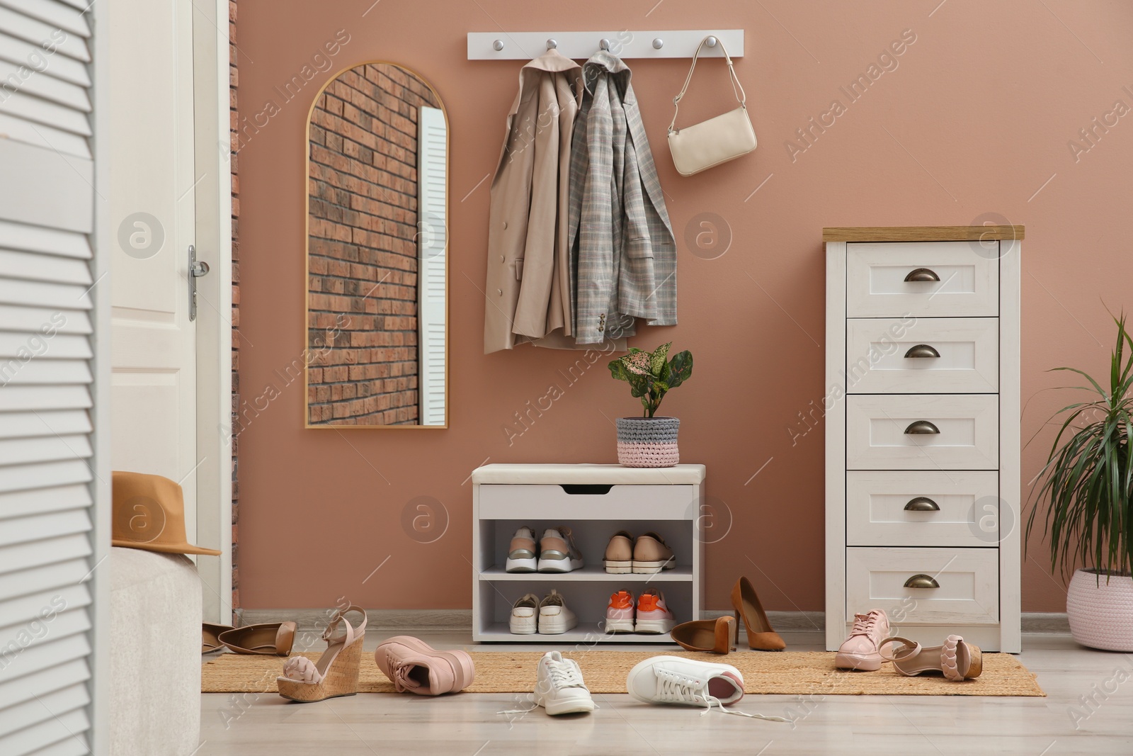 Photo of Stylish furniture and scattered shoes on floor in hall