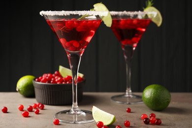 Photo of Tasty cranberry cocktail with rosemary and lime in glasses on grey table against black background