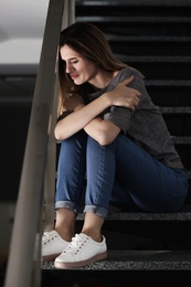 Photo of Lonely depressed woman sitting on stairs indoors
