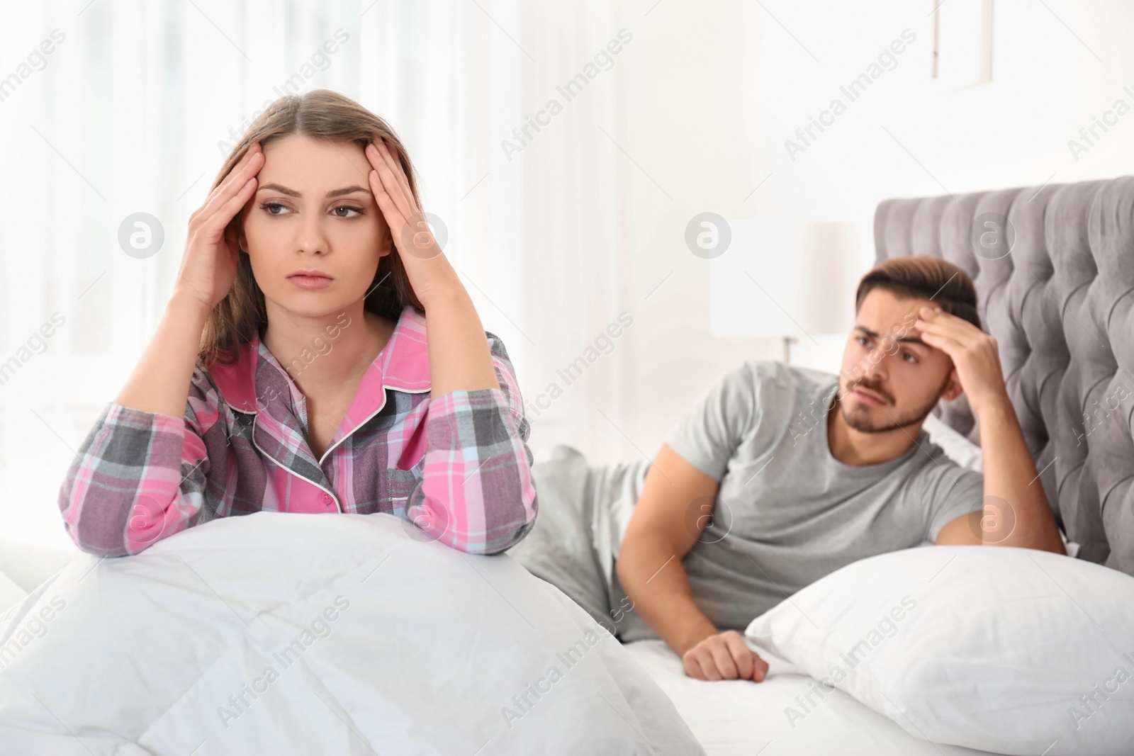 Photo of Young couple with relationship problems ignoring each other in bedroom
