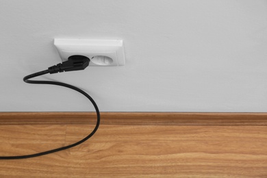 Photo of Power socket and plug on wall indoors, space for text. Electrician's equipment