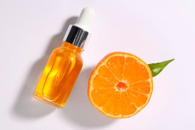 Photo of Aromatic tangerine essential oil in bottle and citrus fruit on white table, top view