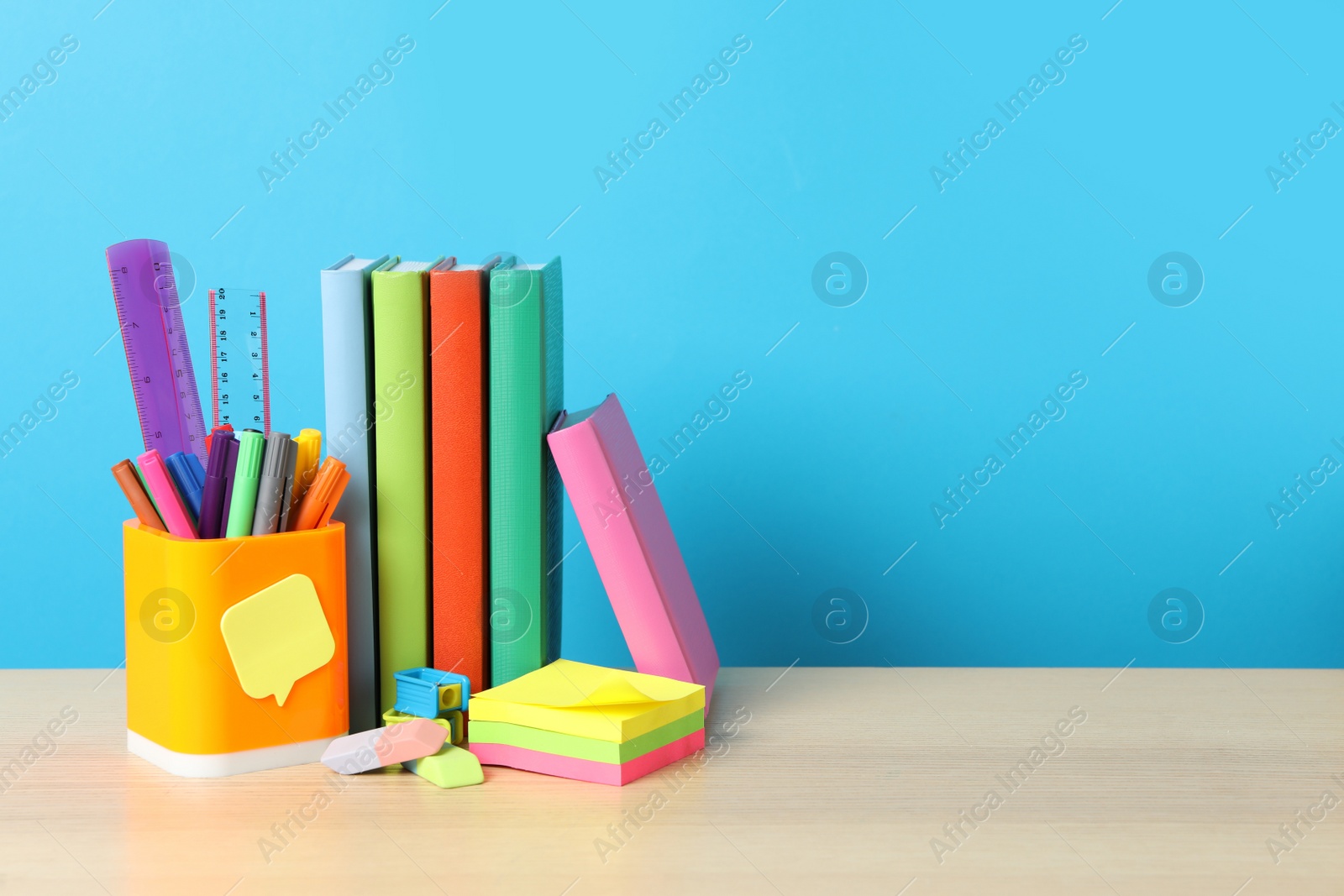 Photo of Composition with different school stationery on wooden table against light blue background, space for text. Back to school