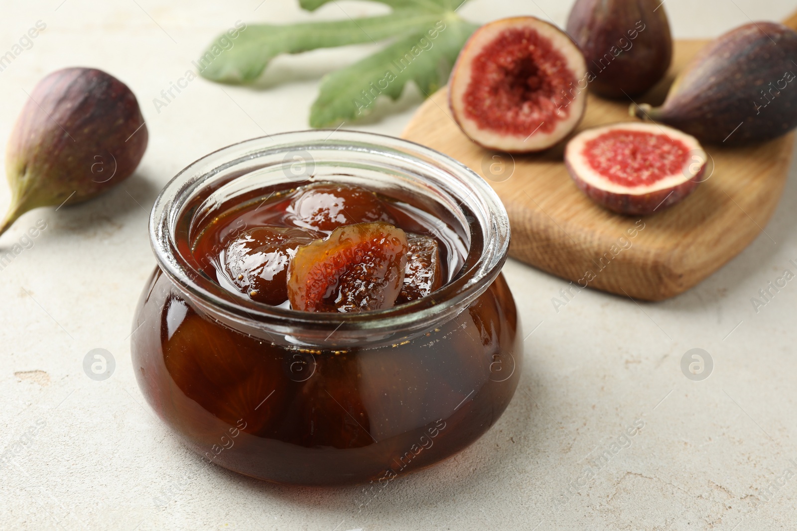 Photo of Jar of tasty sweet jam and fresh figs on white table