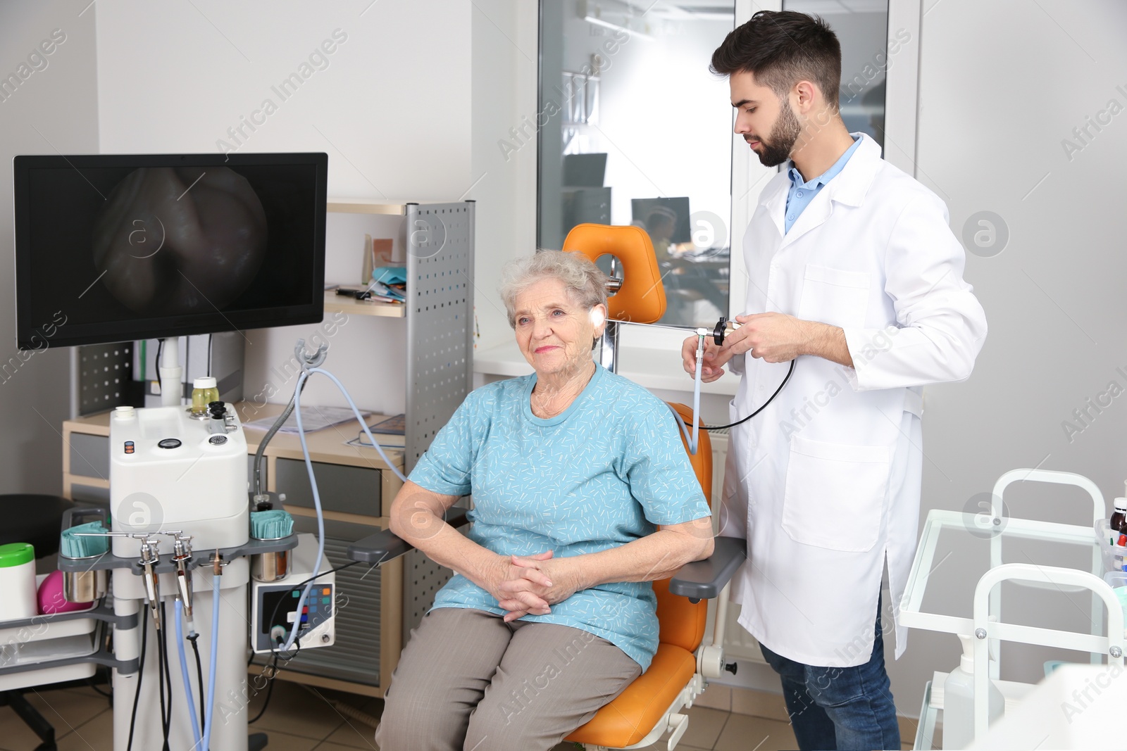 Photo of Professional otolaryngologist examining senior woman with endoscope in clinic. Hearing disorder