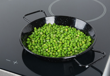 Photo of Cooking frozen sweet peas on induction stove. Vegetable preservation
