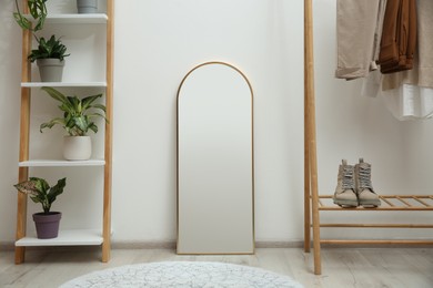 Photo of Dressing room interior with wooden furniture, mirror and houseplants near white wall. Stylish accessories