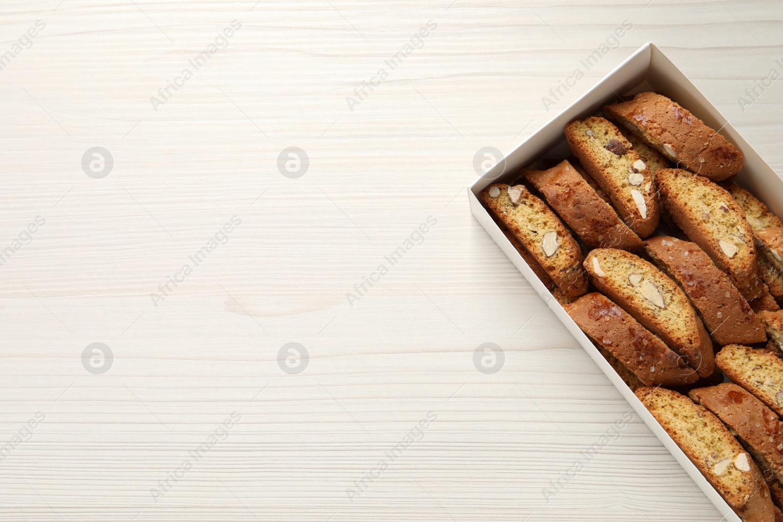 Photo of Traditional Italian almond biscuits (Cantucci) on white wooden table, top view. Space for text