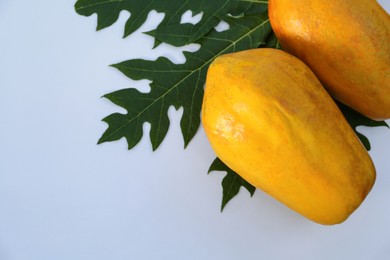 Fresh ripe papaya fruits and leaf on white background, flat lay. Space for text