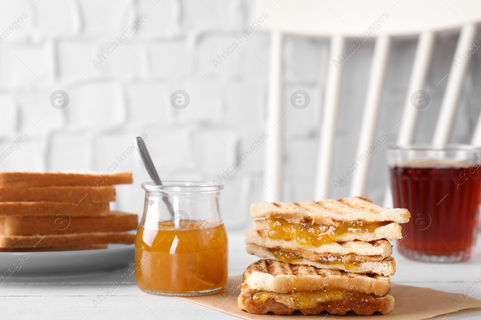 Image of Tasty sandwiches with apricot jam and peanut butter for breakfast on white table