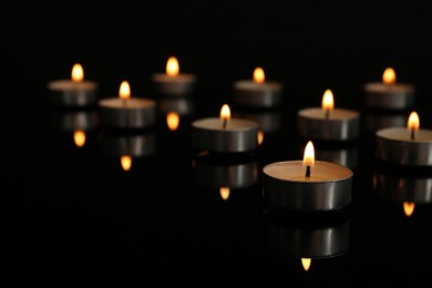 Photo of Small burning candles on table in darkness, space for text