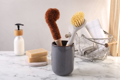 Photo of Brushes in holder and cleaning tools on white marble table