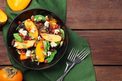 Photo of Delicious persimmon salad and forks on wooden table, flat lay. Space for text