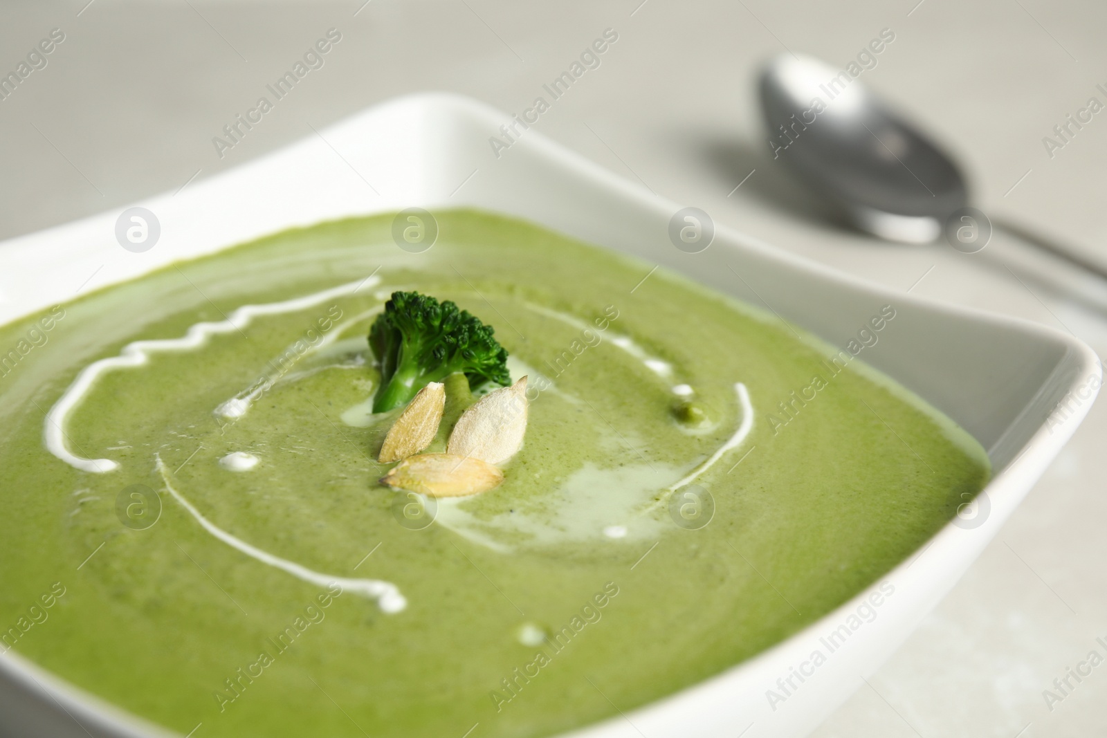 Photo of Bowl of delicious broccoli cream soup with pumpkin seeds, closeup