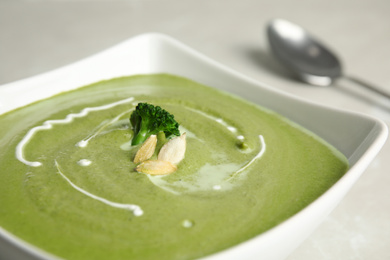 Photo of Bowl of delicious broccoli cream soup with pumpkin seeds, closeup