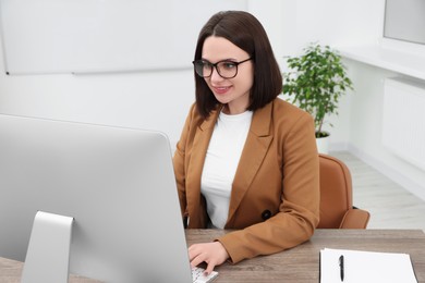 Photo of Happy young intern working with computer at table in modern office