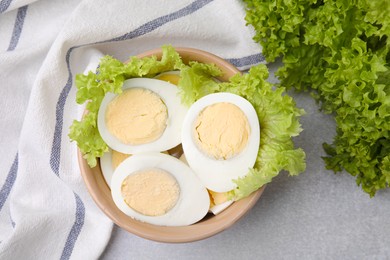 Photo of Fresh hard boiled eggs and lettuce on light grey table, top view