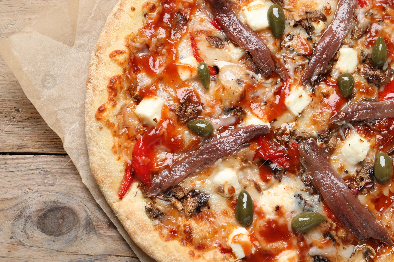 Photo of Tasty pizza with anchovies and olives on wooden table, top view