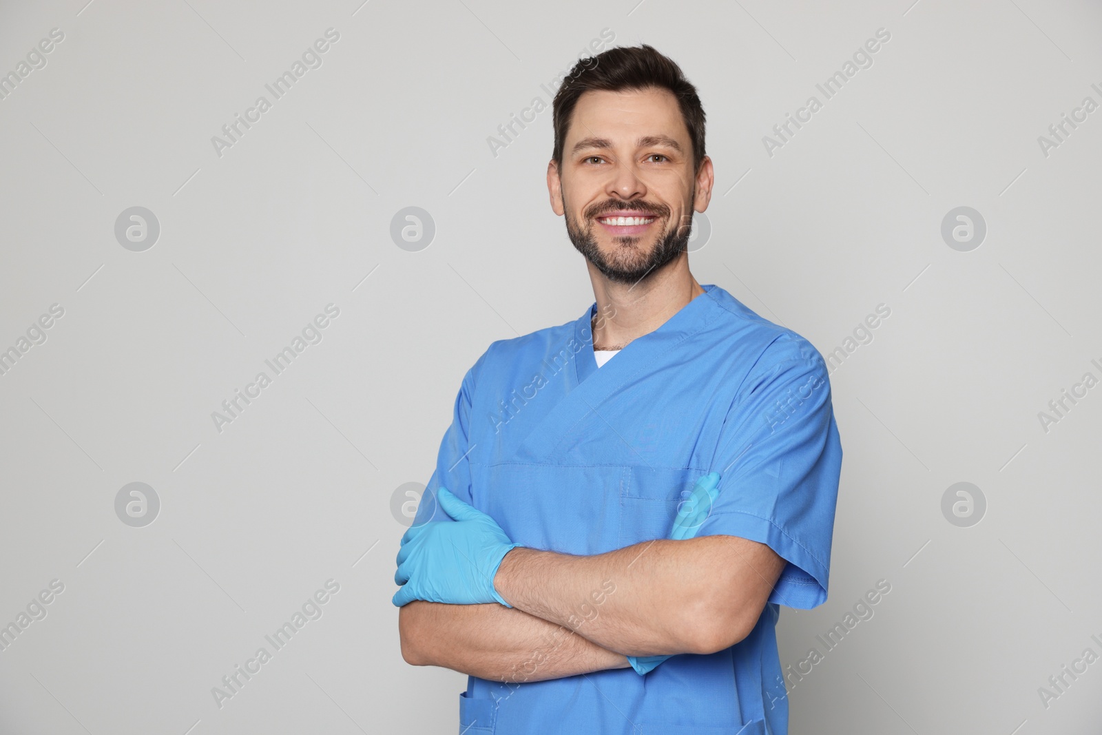 Photo of Doctor or medical assistant (male nurse) in uniform on light grey background. Space for text