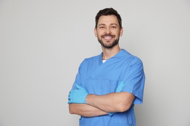 Photo of Doctor or medical assistant (male nurse) in uniform on light grey background. Space for text