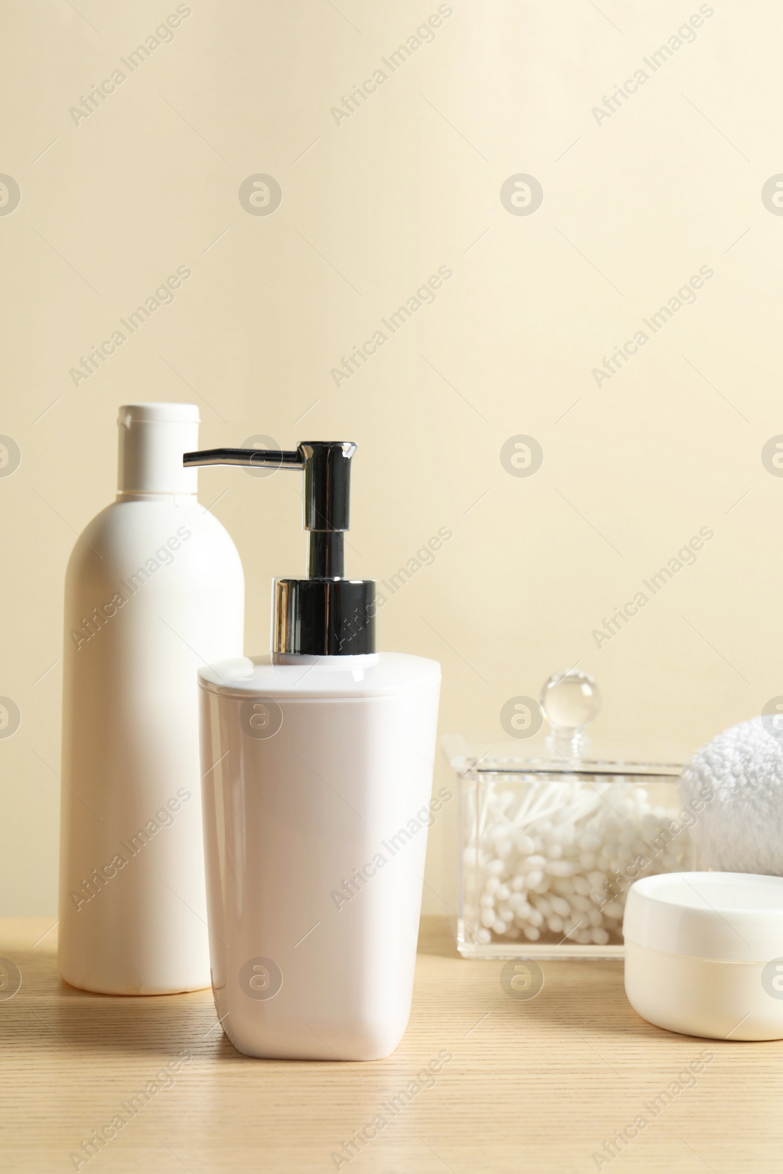 Photo of Different bath accessories on wooden table against beige background