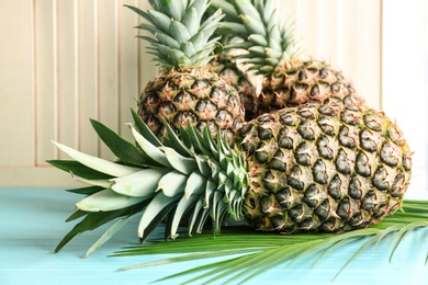 Photo of Fresh pineapples on table against light wall, closeup